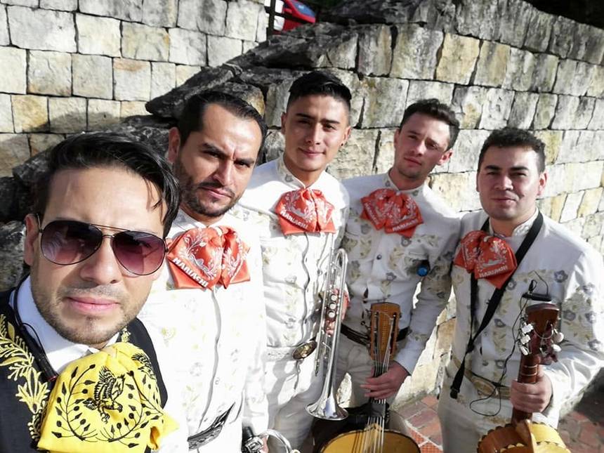 Los cinco integrantes del mariachi juvenil de Bogotá con traje de gala y moños rojos
