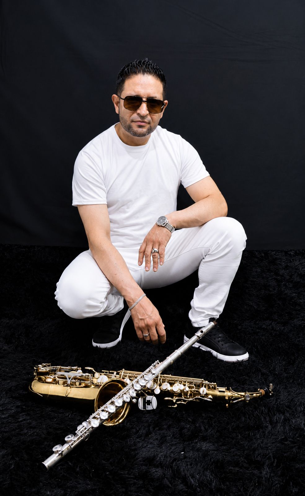 Saxofonista de Bogotá sentado junto a su saxofón alto dorado y su flauta traversa
