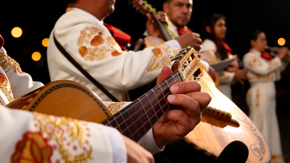 Primer plano de las manos de un músico tocando la vihuela durante una serenata